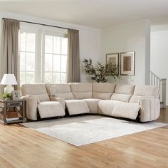 a living room with a large sectional couch in the center and windows to the side