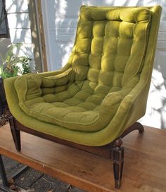 a green chair sitting on top of a wooden table