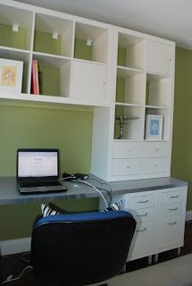 a laptop computer sitting on top of a desk next to a book case and chair