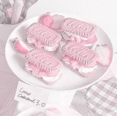 there are some pink desserts on a white plate with candy in the shape of hearts