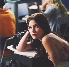 a young woman sitting at a table with a sewing machine on it's side