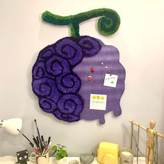 a purple piece of art hanging on the side of a wall next to other items