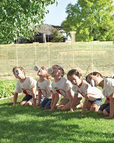 a group of young children sitting on the grass drinking water from plastic bottles in front of them