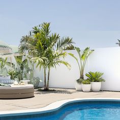 an outdoor pool with lounge chairs and umbrellas next to the side of the swimming pool