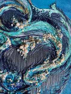 a close up view of the feathers and beads on this piece of art that has been made to look like something out of fabric