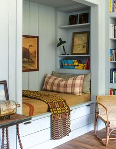 a room with a bed, chair and bookshelf filled with lots of books