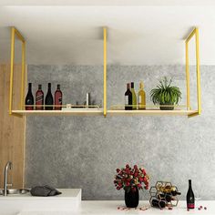 a kitchen with yellow shelves and bottles on the counter top next to a vase filled with flowers