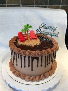 a birthday cake is decorated with chocolate icing and palm trees on the top layer