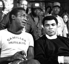 two men sitting next to each other in front of a group of people wearing glasses