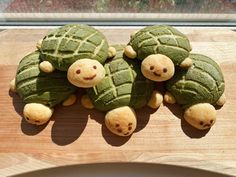 three green tortoise shell shaped animals on top of a wooden table next to a window