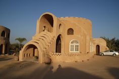 a car is parked in front of an adobe - style building with arches and arched windows