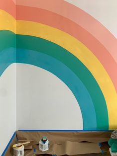 there is a rainbow painted on the wall in this room with paint rollers next to it