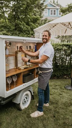 a man standing in front of a white truck filled with wine glasses and an ice cream cart