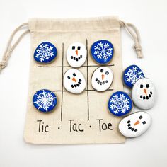 snowmen are painted on rocks in front of a drawstring bag that says tic tac toe