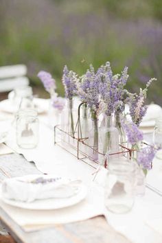 lavender flowers are in mason jars on a table set for an outdoor dinner or brunch