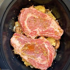 two raw meats in a slow cooker with potatoes and seasoning on top