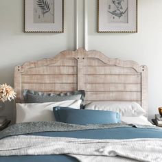 a bed with two pictures on the wall above it and a blue comforter in front