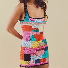 a woman in a colorful crochet dress posing for the camera with her hands on her hips