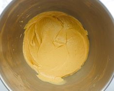 a metal bowl filled with yellow batter on top of a counter