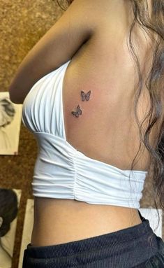 a woman with a small butterfly tattoo on her left side ribcage is shown