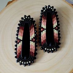 two black, white and red beaded earrings sitting on top of a piece of wood