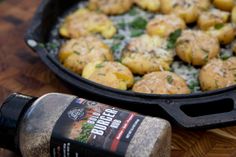 a close up of food in a pan on a wooden table next to a bottle of seasoning