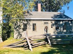 a small gray house with a wooden fence around it