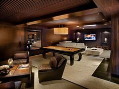 a game room with a pool table, couches and tables in the middle of it