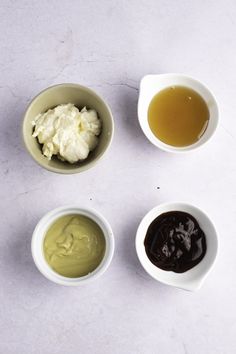 four bowls filled with different types of sauces on top of a white countertop