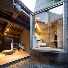 a man is standing in the window of a modern house with wooden floors and walls