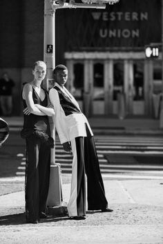 two women standing next to each other near a street light with their arms around each other