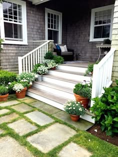 the front steps are lined with potted plants and flowers on either side of the house