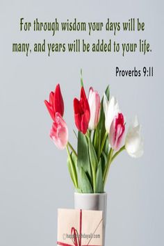 a vase filled with tulips sitting on top of a table next to a card