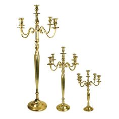 three brass candelabra with candlesticks on each side and one candle holder in the middle