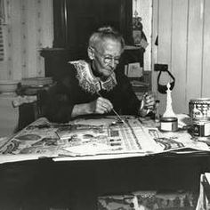 an old woman is sitting at a table working on some art work in her home