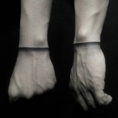 a black and white photo of someone's hands with tattoos on their wrists