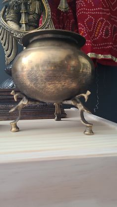 an antique brass urn sitting on top of a white table next to a mirror