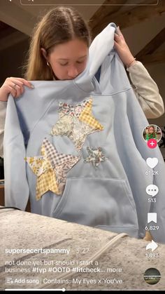 a woman holding up a blue shirt with stars on it