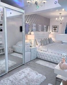 a bedroom with white furniture and chandelier hanging from the ceiling in front of a mirrored wall