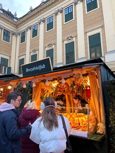 people are standing in front of an outdoor food stand that has been decorated for christmas