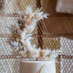 a white wedding cake decorated with flowers and feathers