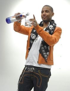 a man in an orange jacket is holding a water bottle and giving the peace sign