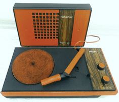 an old fashioned record player with orange trim and wooden case sitting on top of a table