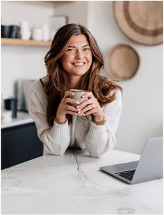 a woman sitting at a table holding a cup