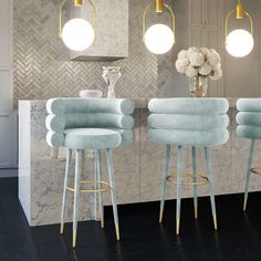 three light blue stools in front of a marble bar with flowers on the counter