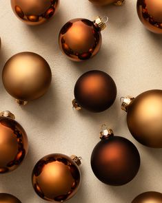 many shiny brown christmas ornaments on a white surface