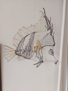 a fish made out of wire hanging on the wall