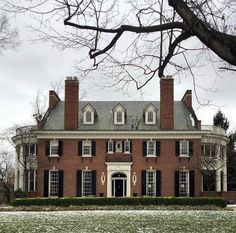 a large red brick house with black shutters on the front and side windows in winter