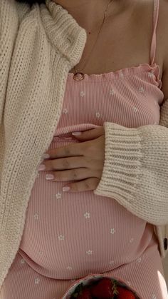 a pregnant woman holding a bowl of strawberries