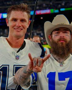 two men with tattoos and cowboy hats standing next to each other at a football game